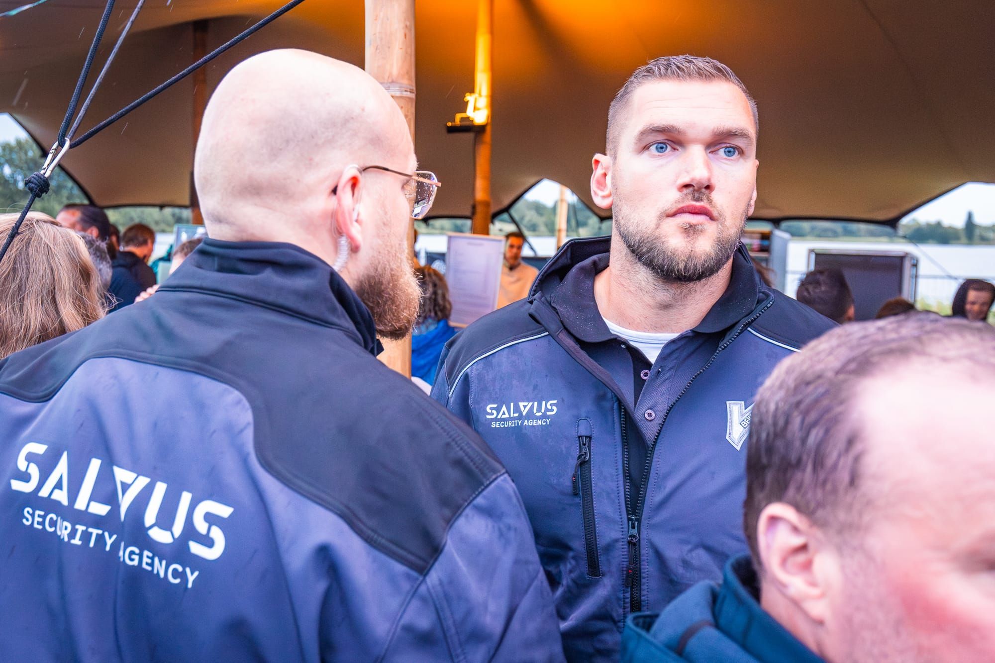 Salvus-beveiligers in overleg in de verlichte tent aan het water
